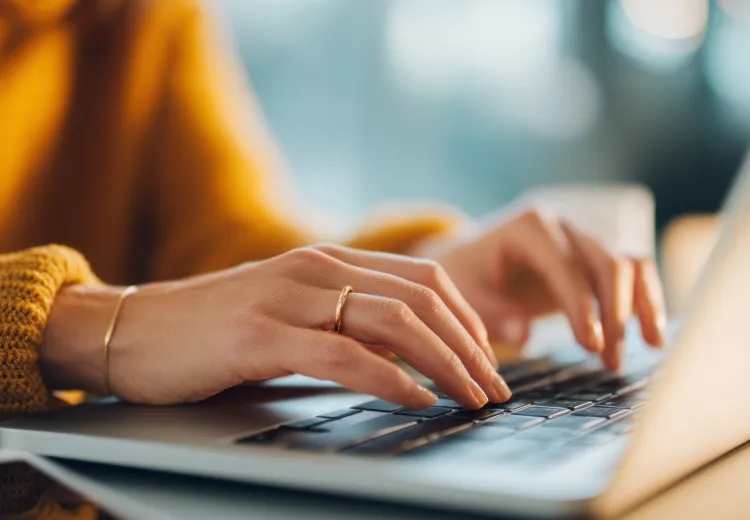 Person's hands typing on a computer keyboard.