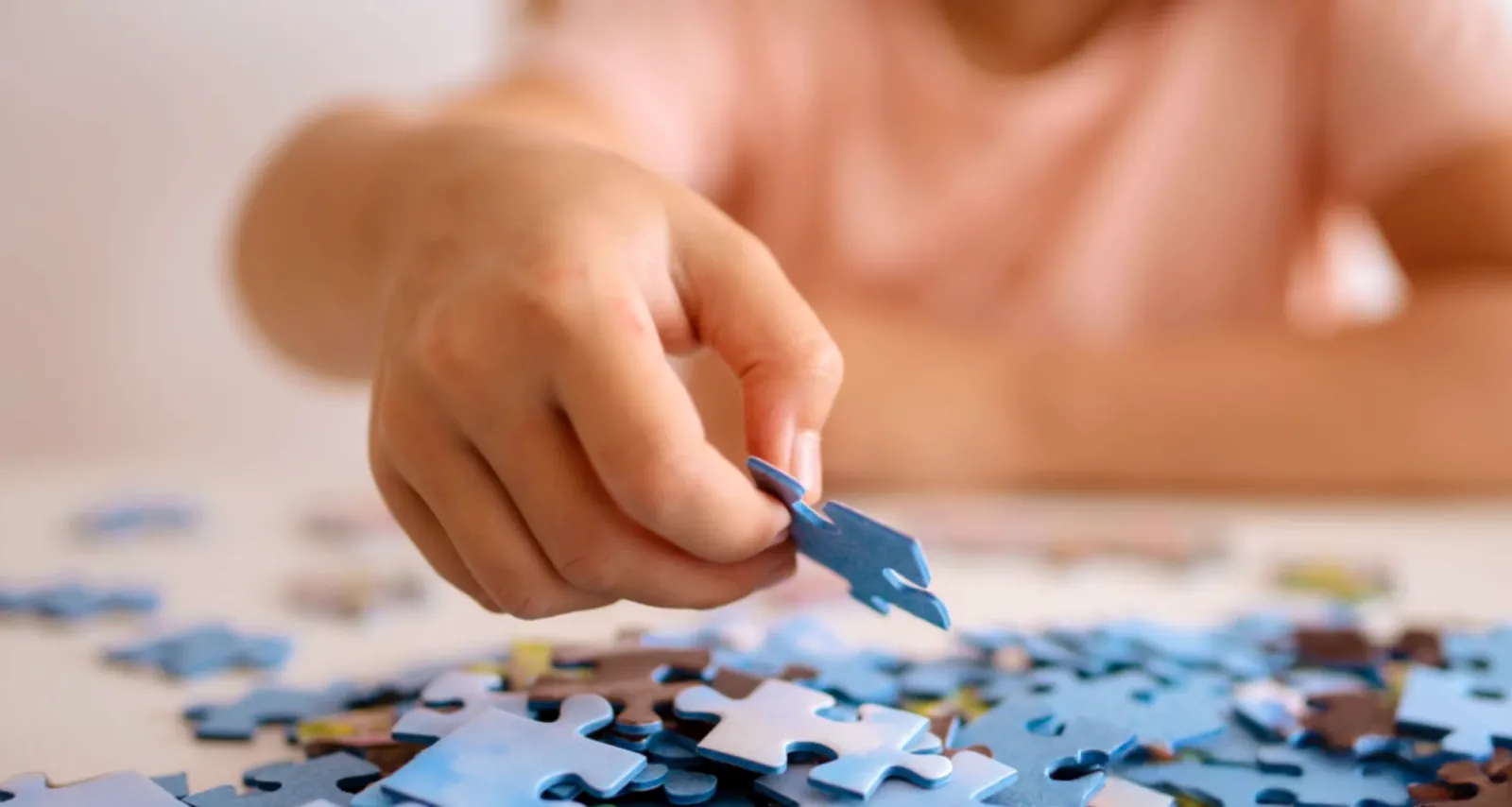 Child's hand adding a puzzle piece that they are building