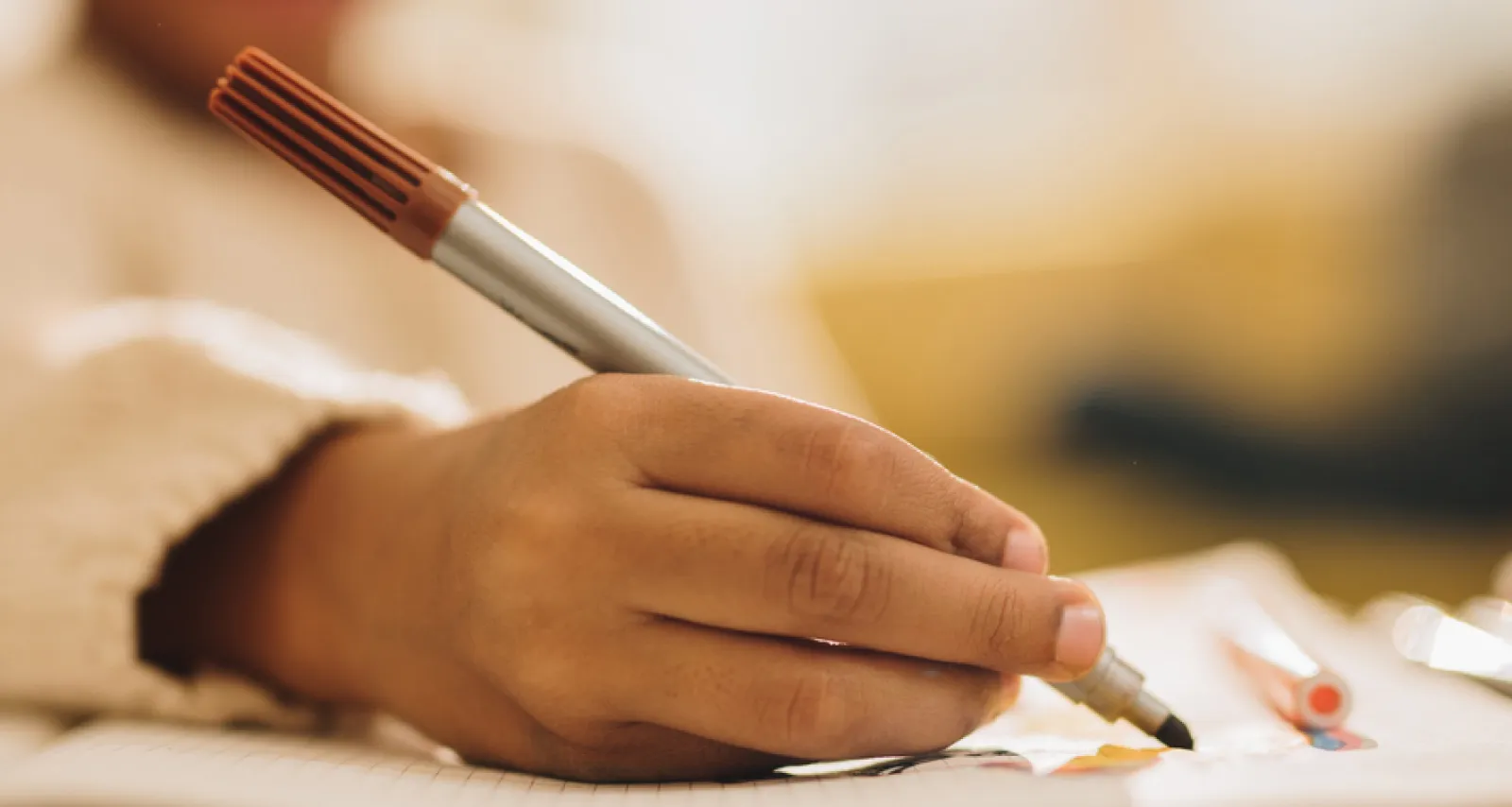 Child's Hand holding a marker, drawing a picture on a piece of paper