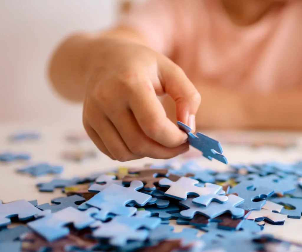 Child's hand adding a puzzle piece that they are building