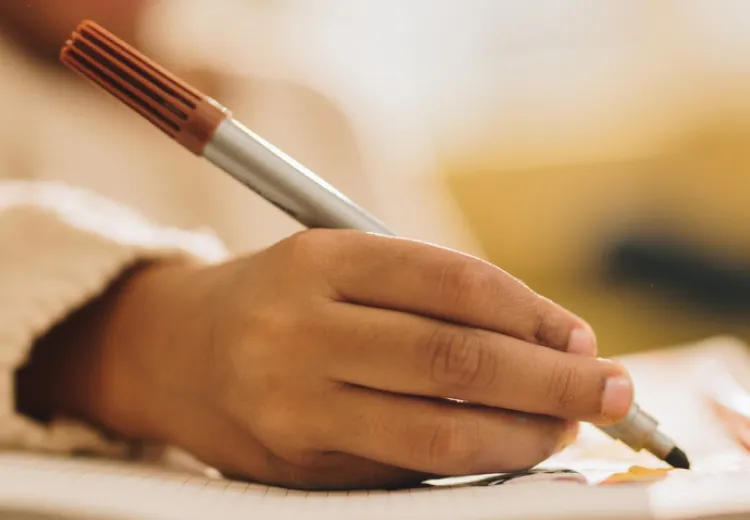 Child's Hand holding a marker, drawing a picture on a piece of paper